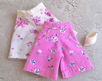 May include: Two pairs of floral print shorts. One pair is white with pink flowers and the other is pink with white flowers.