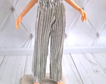 May include: Silver pleated trousers for a doll. The trousers have a wide leg and a comfortable elastic waistband.