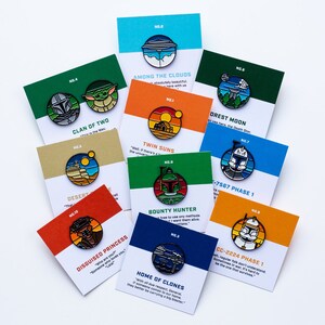May include: A collection of ten enamel pins featuring characters and scenes from Star Wars. The pins are colorful and feature a variety of designs, including the Death Star, a bounty hunter, and a group of clones. Each pin has a number and a quote from the Star Wars universe.