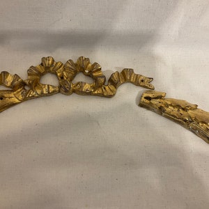 May include: A gold-colored metal decorative trim with a floral design. The trim is broken into two pieces.