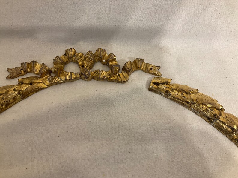May include: A gold-colored metal decorative trim with a floral design. The trim is broken into two pieces.
