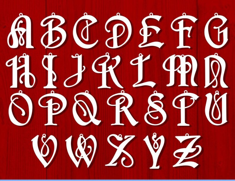 K&ouml;nnte beinhalten: Wei&szlig;e, dekorative, kursive Buchstaben des Alphabets mit einem Loch oben zum Aufh&auml;ngen. Die Buchstaben befinden sich auf einem roten Holzgrund.