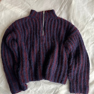May include: A blue and red striped knit sweater with a half-zip closure. The sweater has a relaxed fit and a cropped length.
