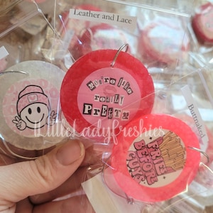 May include: Two pink and red round resin ornaments with silver rings. One ornament has the text "You're like really Pretty" and the other has the text "Fries before guys".