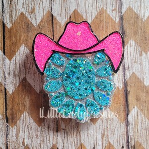 May include: A turquoise glitter cowboy hat with a pink glitter brim. The hat is a craft supply and is perfect for adding a touch of whimsy to any project.