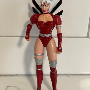 May include: A red and silver action figure of a female superhero with white hair and a black and silver wing design on her back.