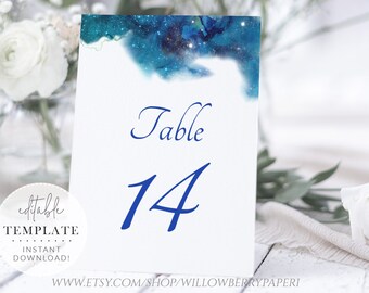 May include: A white card with a blue watercolor galaxy design. The card says "Table 14" in blue cursive text.