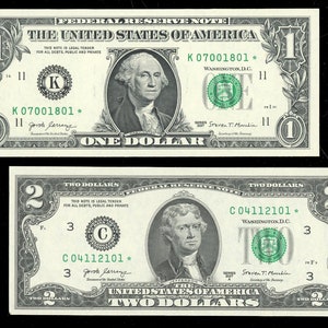 May include: Two US dollar bills, one with a portrait of George Washington and the other with a portrait of Thomas Jefferson. The bills are both in good condition and have the serial numbers K07001801 and C04112101.