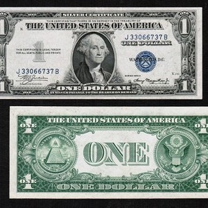May include: Two US dollar bills, one a silver certificate with a portrait of George Washington and the text "The United States of America" and "One Dollar", the other a green bill with the text "The United States of America" and "One Dollar".