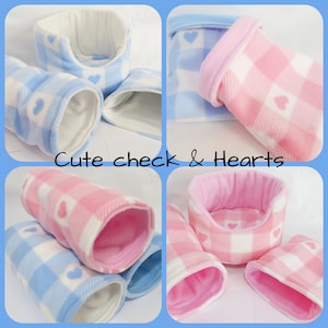 Pode incluir: Um conjunto de camas e túneis para animais de estimação de lã rosa e azul com um padrão de xadrez branco e rosa e corações brancos.  "Cute check & Hearts" está escrito em branco sobre um fundo preto.