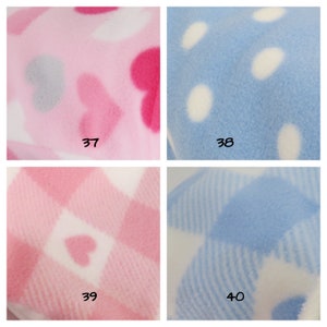 May include: Four fabric swatches with different patterns. The top left swatch is pink with white and pink hearts. The top right swatch is light blue with white polka dots. The bottom left swatch is white with pink and white checkered pattern and pink hearts. The bottom right swatch is white with light blue and white striped pattern.
