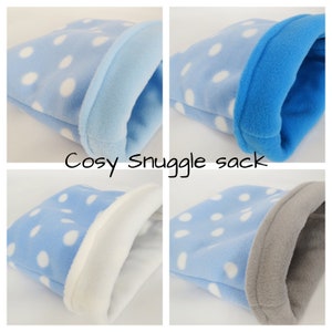 Könnte beinhalten: Vier blaue Kuschelsäcke mit weißen Punkten und verschiedenen Farbkanten. Die Kantenfarben sind weiß, blau, grau und hellblau. Der Text "Cosy Snuggle sack" ist unter dem Bild gedruckt.