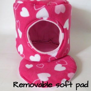 May include: Pink and white heart patterned fleece pet bed with a removable soft pad. The bed has a round opening for the pet to enter.