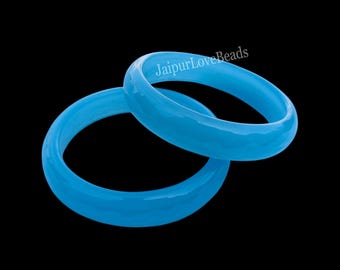 May include: Two light blue bangles with a faceted surface are displayed against a black background. The text "JaipurLoveBeads" is visible on the top bangle. These bracelets are a stylish accessory.