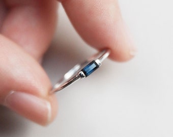 May include: A silver ring with a single, rectangular blue gemstone.
