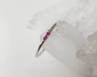 Anello in platino con zaffiro rosa taglio baguette: fede nuziale minimalista da indossare sopra altri anelli.