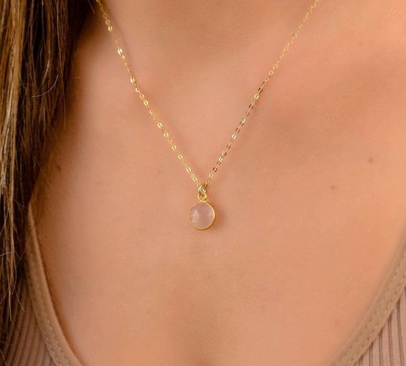 May include: A delicate gold chain necklace with a small, round, clear gemstone pendant.