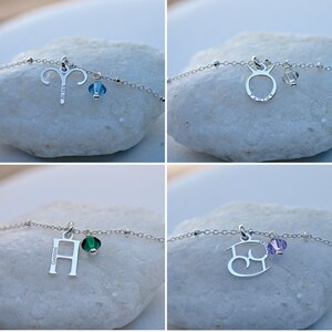 Puede incluir: Cuatro collares de plata con signos del zod&iacute;aco y dijes de cristal. Los collares presentan los signos Aries, Tauro, G&eacute;minis y C&aacute;ncer. Los dijes son azules, transparentes, verdes y morados.