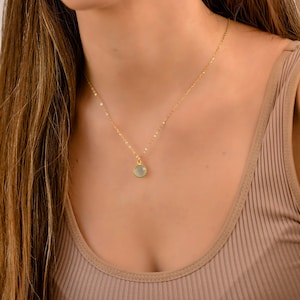 May include: A gold chain necklace with a light green gemstone pendant.
