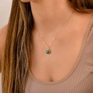 May include: A gold chain necklace with a green gemstone pendant.