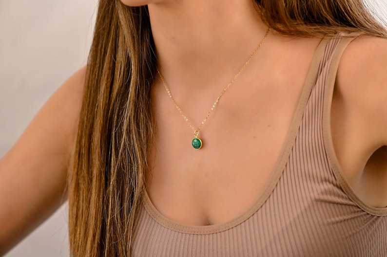 May include: A gold chain necklace with a green gemstone pendant.