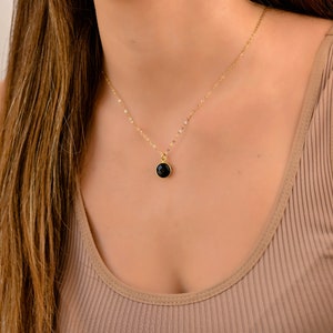 May include: A gold chain necklace with a black gemstone pendant.