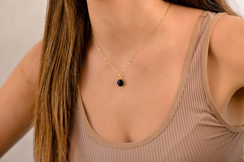 May include: A gold chain necklace with a black gemstone pendant.