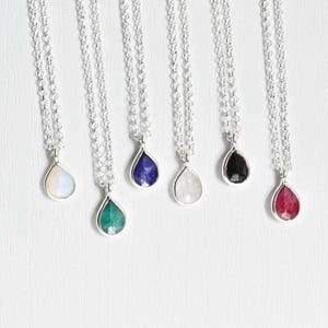 Puede incluir: Seis collares de plata con colgantes de piedras preciosas en forma de lágrima. Las piedras preciosas son de varios colores, incluyendo verde, azul, blanco, negro y rojo.