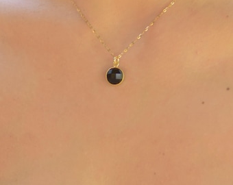 May include: A gold chain necklace with a black oval pendant.