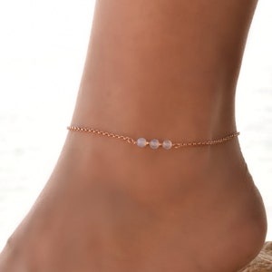 May include: A delicate gold anklet with three small white opal beads.