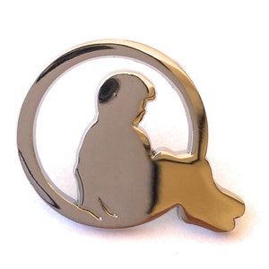 May include: A silver metal pin with a silhouette of a person sitting in a circle.