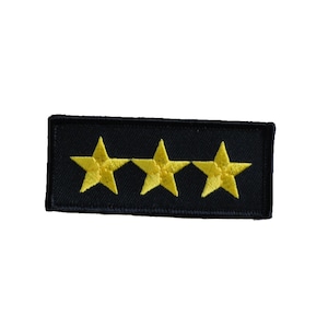 Peut inclure: Un patch rectangulaire noir avec trois étoiles dorées brodées.