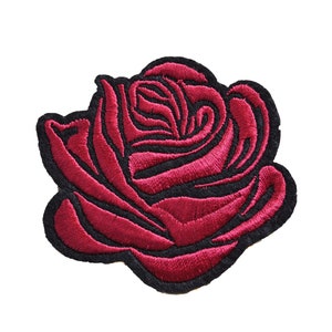 Peut inclure: Un patch brodé de rose rouge avec des contours noirs. La rose est un motif floral classique.