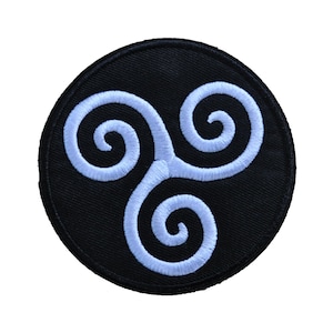 Peut inclure: Écusson rond brodé noir avec un motif triskèle bleu clair. Le triskèle, symbole celtique, est composé de trois spirales entrelacées. Idéal pour les vestes, sacs ou autres articles en tissu.