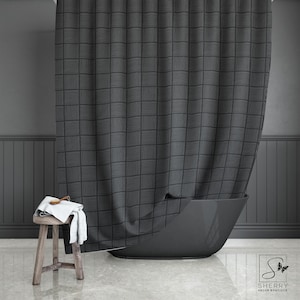 Puede incluir: Una cortina de ducha con un patrón en blanco y negro con un diseño geométrico. La cortina está colgada en un baño con una bañera negra y un taburete de madera.