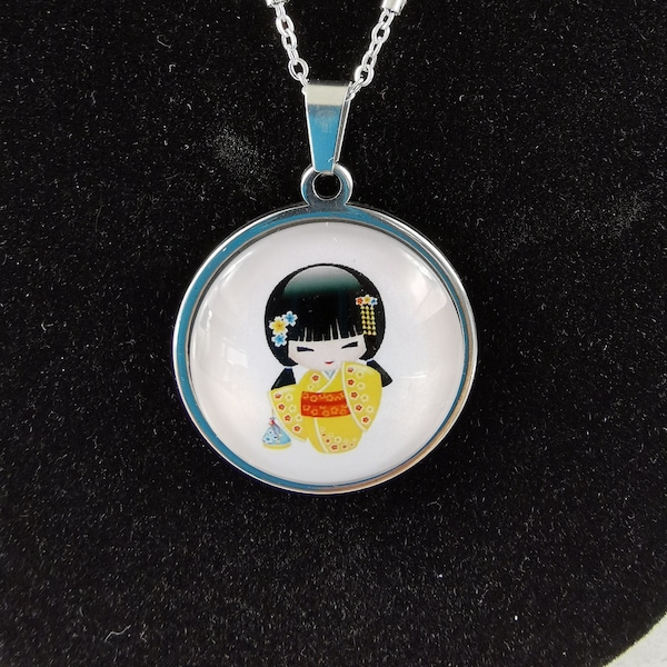 Collier kokeshi au kimono jaune sur fonds blanc avec deux broches fleurs dans les cheveux