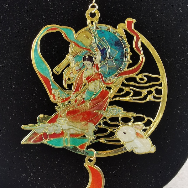 Collier dont le médaillon représente une femme volant sous une lune bleu accompagné d'un lapin blanc et de sa cithare