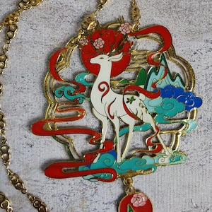 Necklace with a medallion representing a white deer with flowering wood standing in front of a blue mountain on a sea of clouds