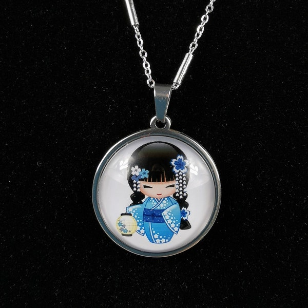 Collier kokeshi au kimono bleu sur fonds blanc avec des broches fleurs dans les cheveux