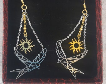 Pair of earrings depicting a silver origami swallow and a golden sun