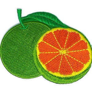 May include: An embroidered patch featuring a whole green citrus fruit with a stem and leaf, partially overlapping a sliced citrus fruit showing a bright orange interior with yellow segments and a green rind border.