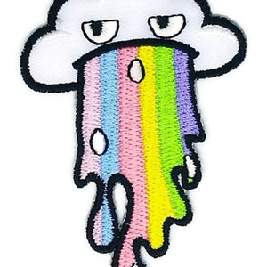 Könnte beinhalten: Ein gestickter Aufnäher, der eine weiße Wolke mit mürrischem Gesichtsausdruck zeigt. Ein lebendiger, mehrfarbiger Regenbogen tropft von der Wolke herab und enthält Schattierungen in Hellblau, Rosa, Gelb, Grün und Violett mit weißen Tropfen.