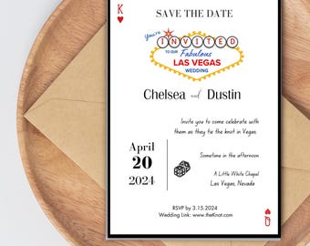 May include: A wedding invitation with a black border, featuring the text "Save the Date" and "Chelsea and Dustin". The design includes a Las Vegas sign graphic and the date April 20, 2024. The invitation is on a wooden tray.