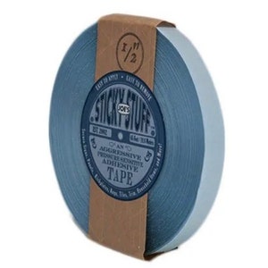 May include: A roll of blue 1/2 inch wide adhesive tape with a brown label that reads "Sticky Stuff Joe's Est. 2002 An Aggressive Pressure Sensitive Adhesive Tape 1/2 inch (12.7 mm) 63 feet (19.2 meters)"