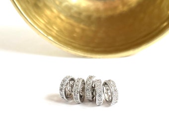 Puede incluir: Cinco anillos de plata con piedras de circonita cúbica transparentes engastadas en un patrón circular.