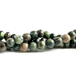 May include: A strand of green and brown marbled round beads. The beads are smooth and polished.