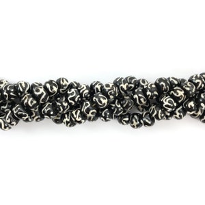 May include: A strand of black and white patterned beads. The beads are round and have a swirling design.