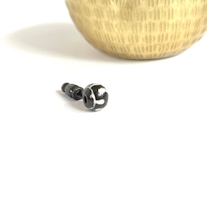 Puede incluir: Una cuenta negra y blanca con un patrón decorativo. La cuenta está unida a un poste de metal negro.