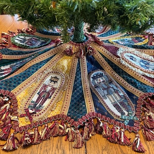 May include: A colorful Christmas tree skirt with a festive design. The skirt features embroidered nutcracker figures and decorative trim in shades of red, gold, and blue. Tassels adorn the edge, adding a touch of elegance to this holiday decor.