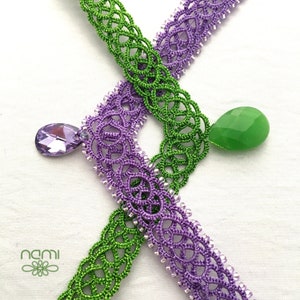 May include: Two handmade crocheted necklaces with a green and purple design. The necklaces are adorned with a green and a purple teardrop-shaped pendant.